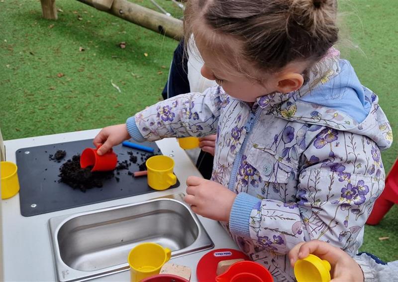 A young girl playing on the mud kitchen for schools